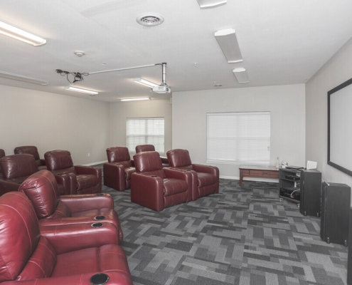 movie theatre themed room with large chairs and a projector at brookhaven senior apartments in indianapolis